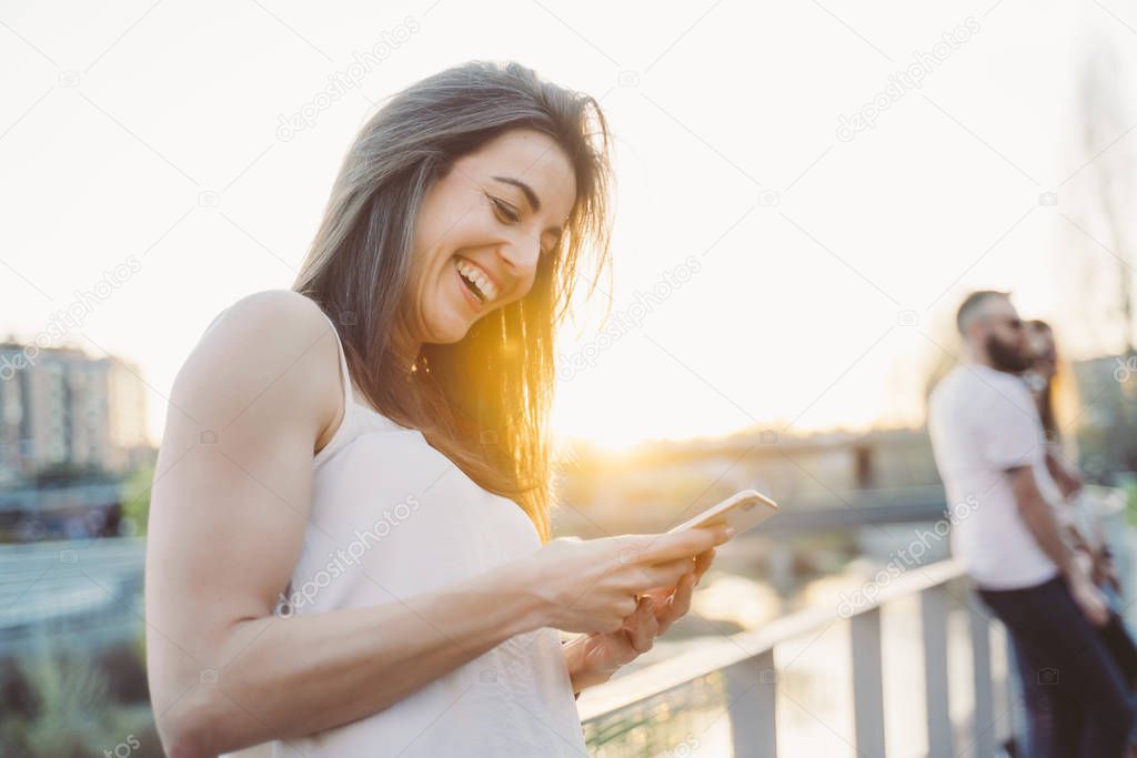 Happy woman texting on smart phone in street