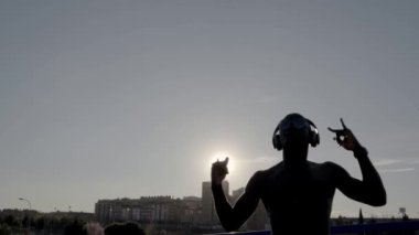 Güneşli bir günde dans Afrika adam. Bazı kulaklık kullanmak