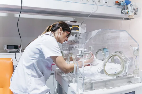 インキュベーターで新生児を検査する女性医師 — ストック写真