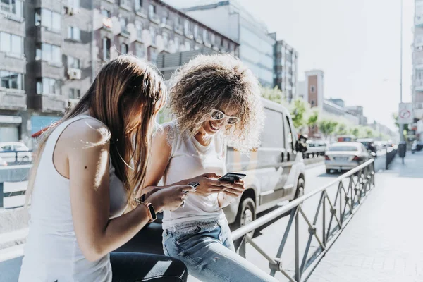 Mulheres bonitas usando um celular na rua. — Fotografia de Stock