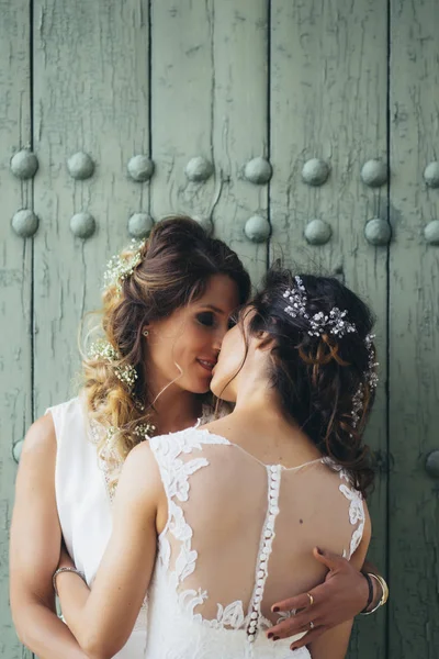 Retrato de um casal orgulhoso beijando uns aos outros com vestidos de noiva brancos — Fotografia de Stock