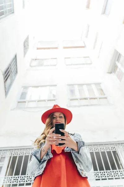 Жінка в червоній сукні на смартфоні на вулиці — стокове фото