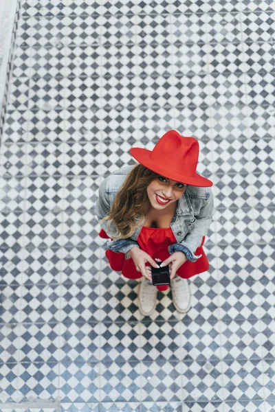 Mulher vestindo vestido vermelho mensagens de texto no telefone inteligente na rua — Fotografia de Stock