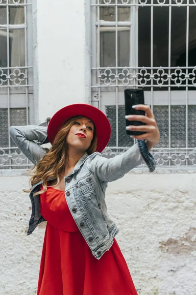 Mulher vestindo vestido vermelho mensagens de texto no telefone inteligente na rua — Fotografia de Stock