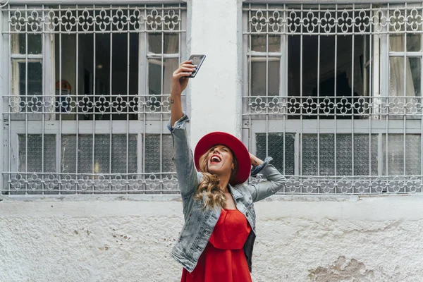 Kobieta w czerwonej sukience smsuje na smartfonie na ulicy — Zdjęcie stockowe