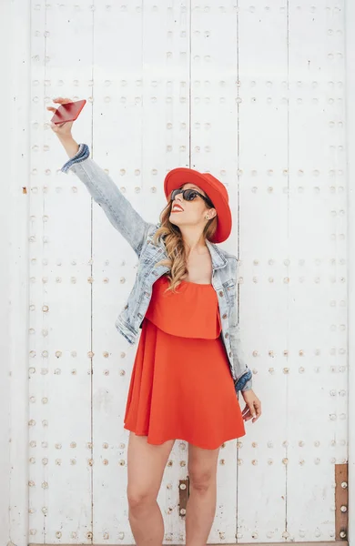 Mujer con vestido rojo mensajes de texto en el teléfono inteligente en la calle — Foto de Stock