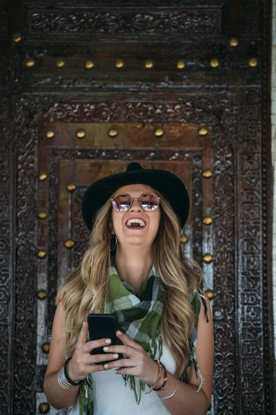 Mulher usando chapéu preto mensagens no telefone inteligente na rua — Fotografia de Stock