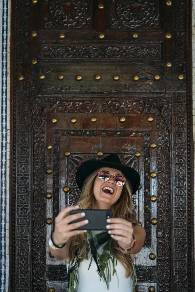 Mulher usando chapéu preto mensagens no telefone inteligente na rua — Fotografia de Stock