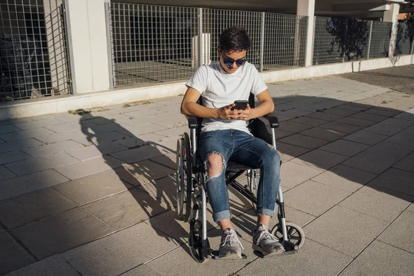 Portrait of cute boy sitting on wheelchair outdoor — ストック写真