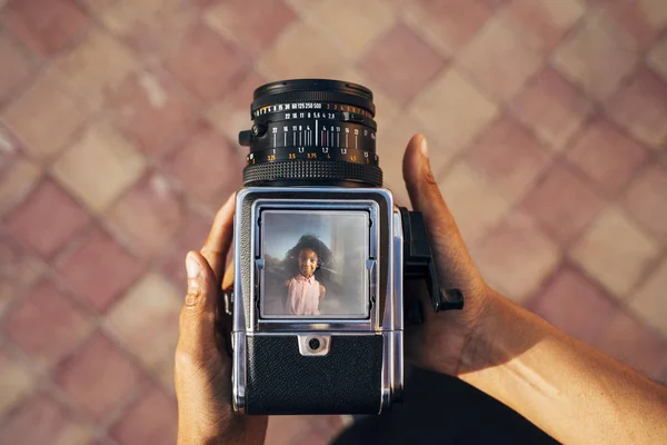 Mirando hacia abajo a una vieja cámara, tomando una foto de una joven afro — Foto de Stock