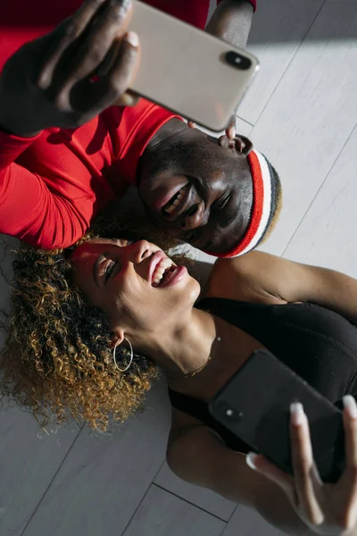 two friends laughing each other on the floor holding the phone and taking pictures of themselves. Close up