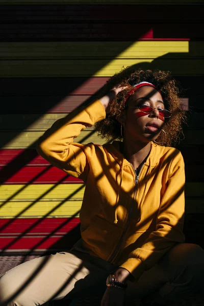 Brown skin woman with a yellow hoodie, shadows and highlights. Urban fashion slyle. — Stock Photo, Image