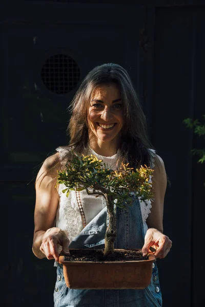 Retrato de una mujer sosteniendo un bonsái con las manos — Foto de Stock