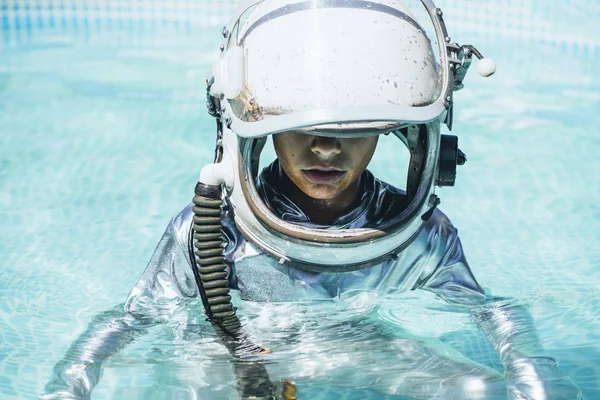 Little boy with astronaut helmet in the water