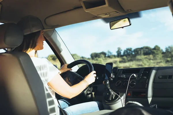 Girl driving orange van. She is wearing a beanie and steering with a large wheel. — Stock Photo, Image