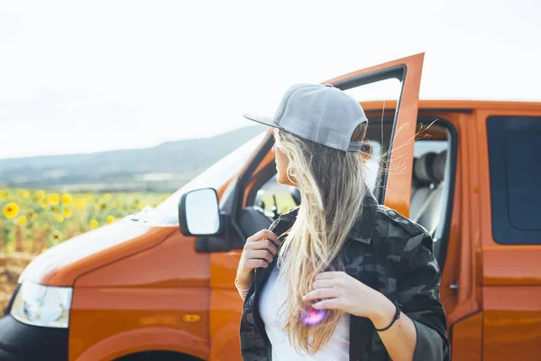 在橙色面包车外面戴帽子的金发美女 — 图库照片