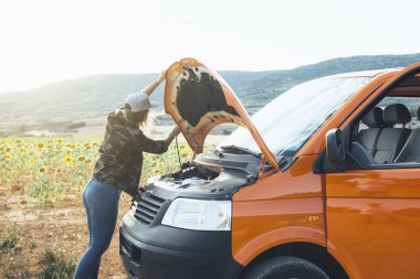 Turuncu minibüsün dışında şapkalı hoş bir sarışın kadın.