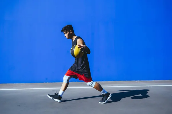 Чоловік грає в баскетбол перед синьою стіною — стокове фото