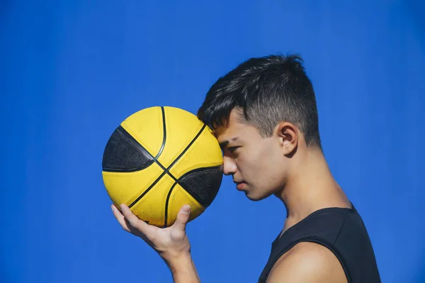 Vista laterale ritratto di un uomo che tiene una palla da basket sulla parete blu — Foto Stock