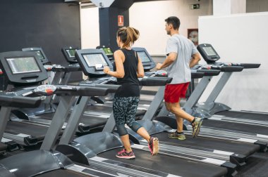 two person running on a treadmill in a gym clipart