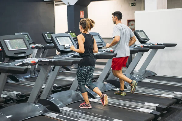 two person running on a treadmill in a gym