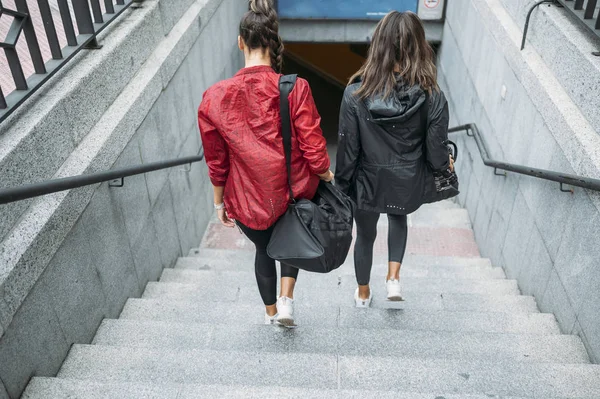 Unrecognizable two woman looking forward while walking down the subway the way to the gym.