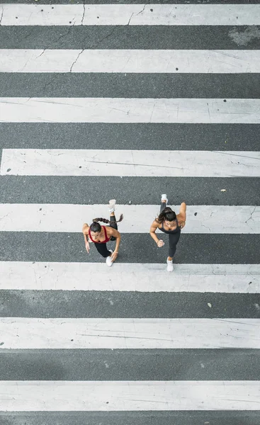 Dos mujeres corriendo hacia el cruce de cebra — Foto de Stock