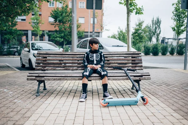 Niño en traje de esqueleto de pie en la calle sentado con scooter — Foto de Stock