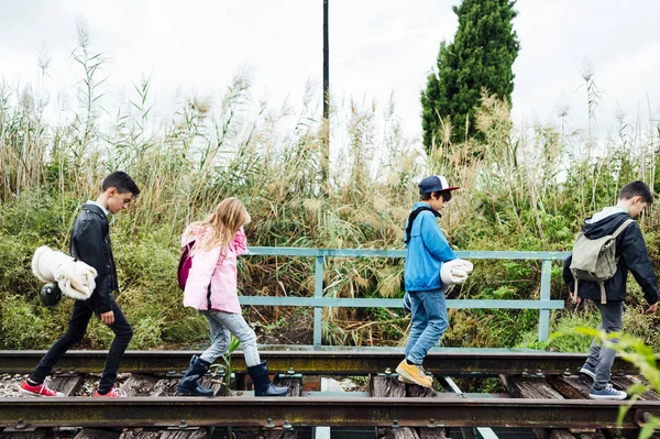 Group of four children hiking in the woods walking in a train track — Stock Photo, Image