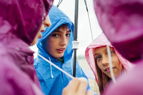 Czterech przyjaciół w płaszczu przeciwdeszczowym w deszczowy dzień — Zdjęcie stockowe