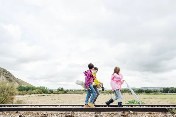Ομάδα από τρία παιδιά πεζοπορία στο δάσος με τα πόδια σε μια σιδηροδρομική γραμμή — Φωτογραφία Αρχείου