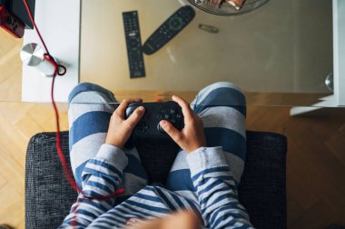 Evde bilgisayar oyunu konsoluyla oynayan tanınmayan bir çocuk.