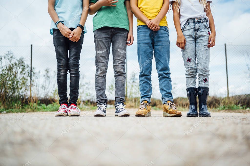 Legs of casual dressed children standing on a road