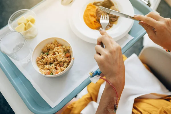 Mujer irreconocible comiendo comida de hospital — Foto de Stock