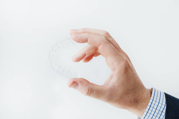 Крупный план нескольких рук, держащих шину, работающих в профессиональной стоматологической лаборатории
