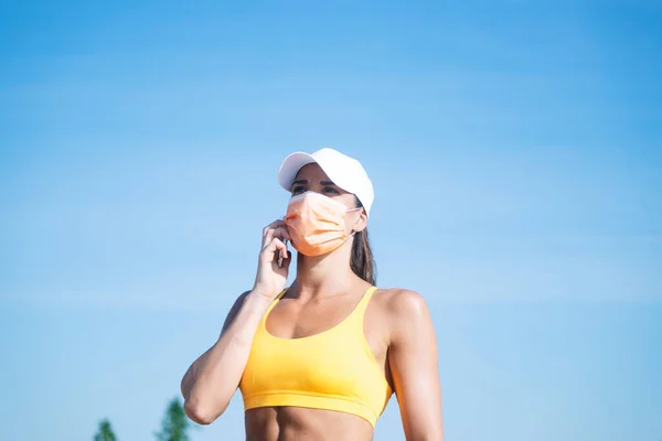 Atletik Kadın Dışarıda Yüz Maskesi Takan Akıllı Telefonunu Kullanıyor — Stok fotoğraf