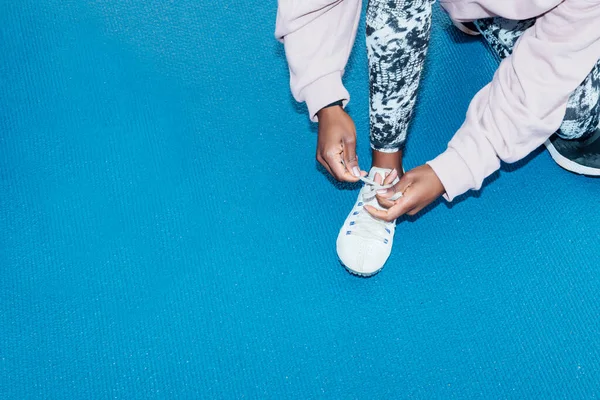 Crop athlete putting on track shoes before sprint