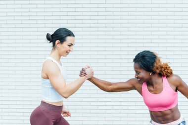 El ele tutuşan iki kadının görüntüsü. Soldaki el beyaz genç bir kadına ait. Sağdaki siyah genç bir bayandan..