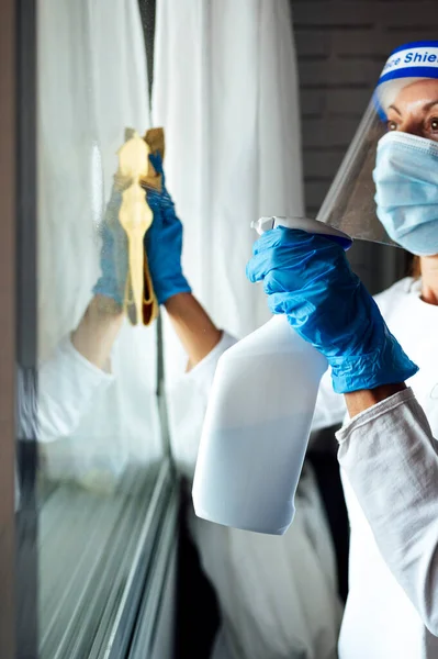 Cleaning staff disinfecting the house against virus, wearing transparent protective mask