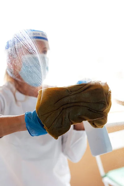 Cleaning staff disinfecting the house against virus, wearing transparent protective mask