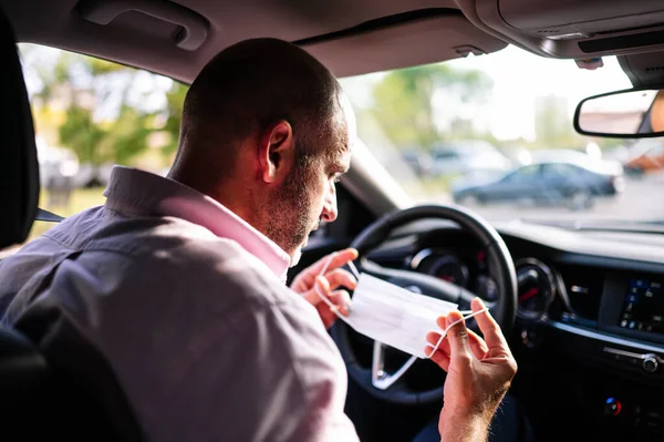 man putting on protective mask in the car