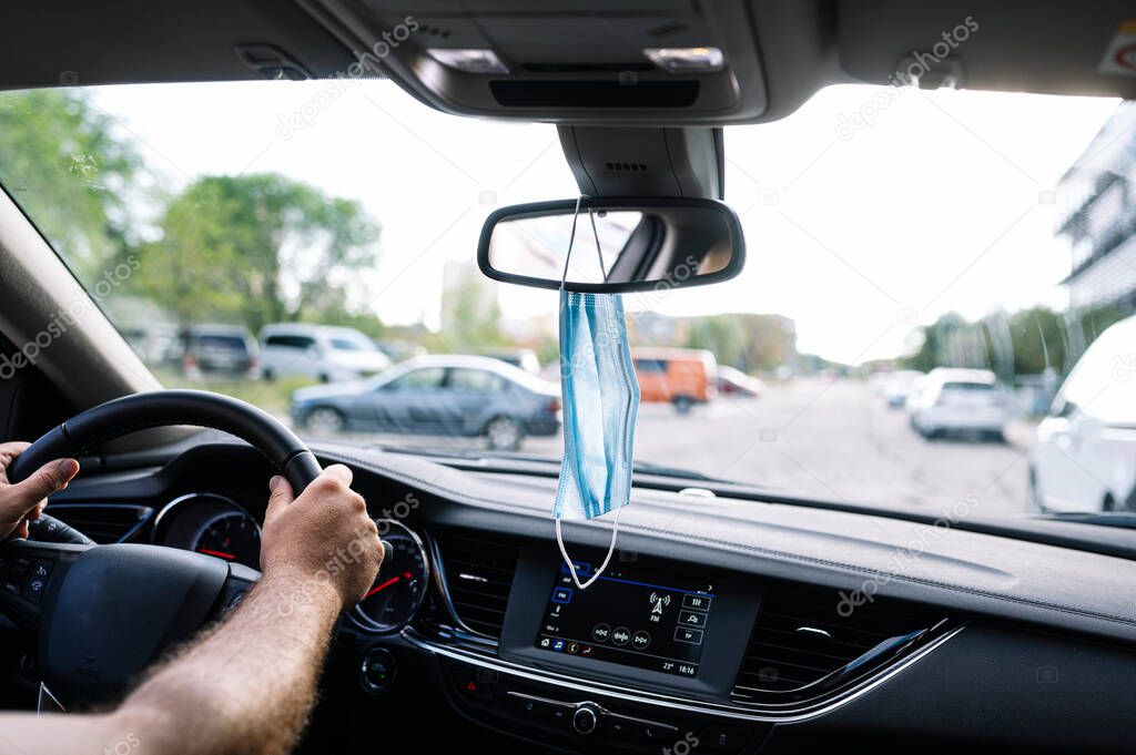 Protective face mask hanging from a car's rear view mirro