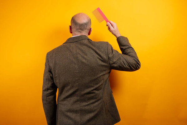 Bald man holding pink comb