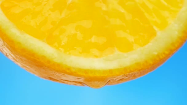 En droppe ren vatten eller juice droppande från en bit av orange — Stockvideo