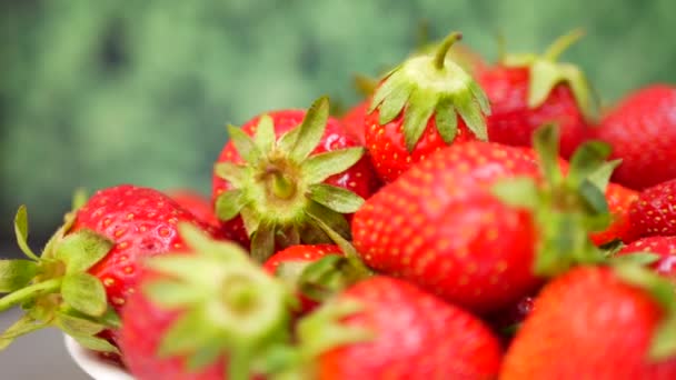 Frische Erdbeeren in einer Schüssel vor grünem Hintergrund — Stockvideo