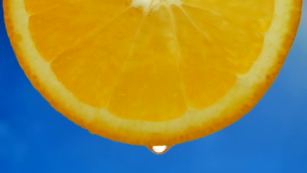 Egy csepp tiszta víz vagy gyümölcslé csöpög egy szelet narancs — Stock videók