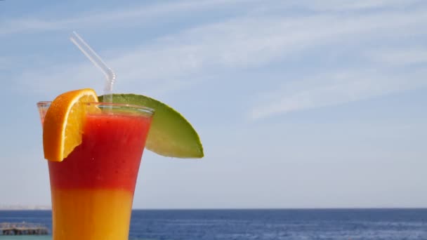 Röd jordgubb och mango juice på blå och turkosa havet bakgrund eller ocean — Stockvideo