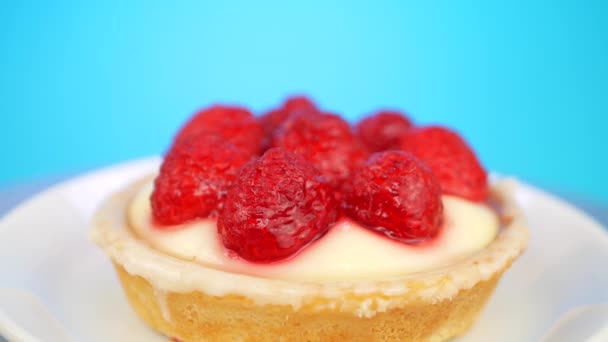 Delicioso y sabroso pastel de esponja con crema de frambuesa y vainilla en la placa blanca gira sobre un fondo verde — Vídeos de Stock