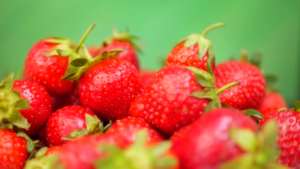 Verse aardbeien in een kom op groene achtergrond — Stockvideo