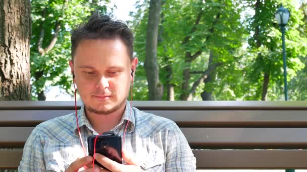 Hombre joven guapo lleva auriculares de música roja — Vídeos de Stock